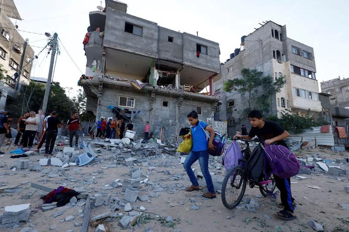 Young Palestinians walk in front of a damaged house in the aftermath of Israeli strikes in Khan Younis in the southern Gaza Strip, October 30, 2023. REUTERS/Mohammed Salem