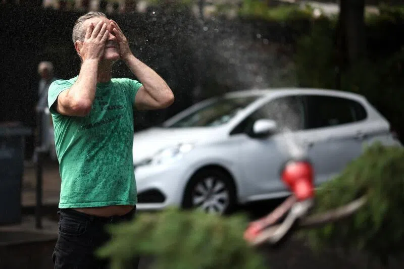A man cools off in front of a hose spraying water in Paris on June 18, 2026.