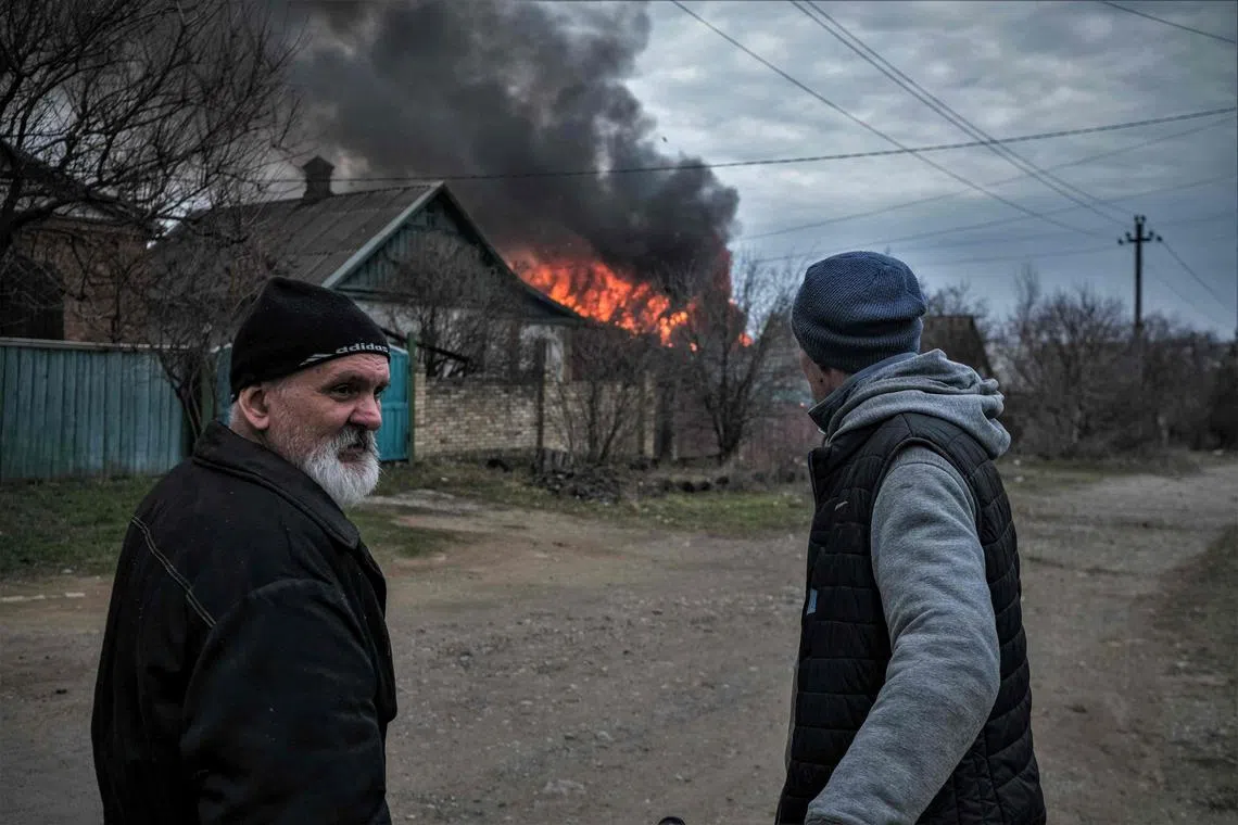 Residents standing near a burning building after an artillery attack in Kostyantynivka, Ukraine, on March 15, 2023.