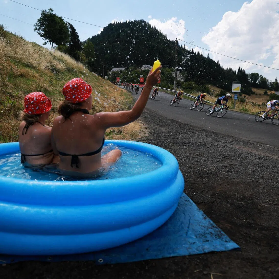 Cyclists in action as spectators in an inflatable water tub cheer on during Stage 10 of the Tour de France from Aurillac to Le Lioran on July 14.