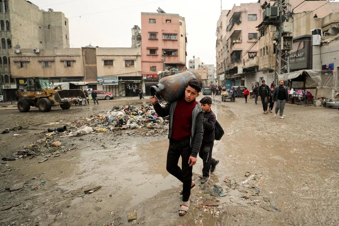 A Palestinian carries a cooking gas cylinder, amid a ceasefire between Hamas and Israel, in Gaza City, February 3, 2025. REUTERS/Dawoud Abu Alkas