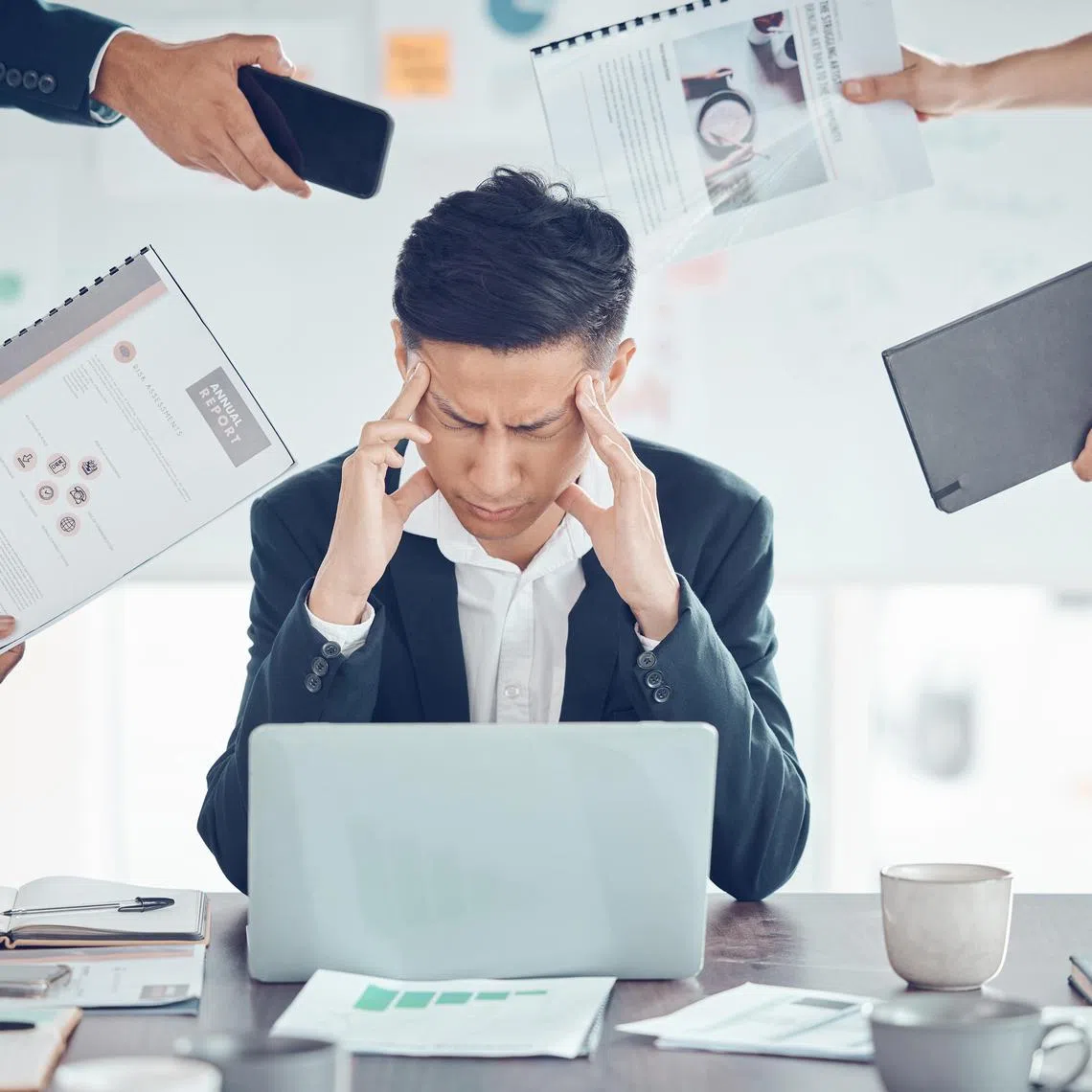 akbooks - Istockphoto - Stress, tired and business man with burnout, headache and frustrated work pressure with hands of employees giving task. Manager, mental health and data analyst male stressed and depressed at desk