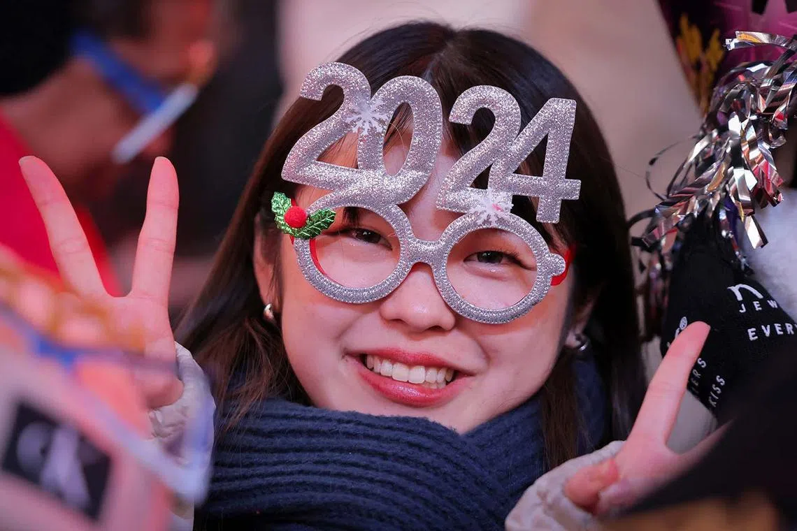A reveller wearing 2024 glasses gestures in Times Square ahead of celebrations of the New Year's Eve, in New York City, New York, U.S., Dec 31, 2023.