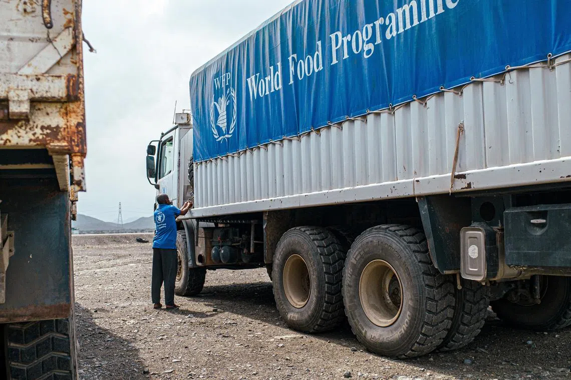 FILE PHOTO: A WFP worker stands next to a truck carrying aid from Port Sudan to Sudan, in Sudan November 12, 2024. WFP/Abubakar Garelnabei/Handout via REUTERS/File Photo