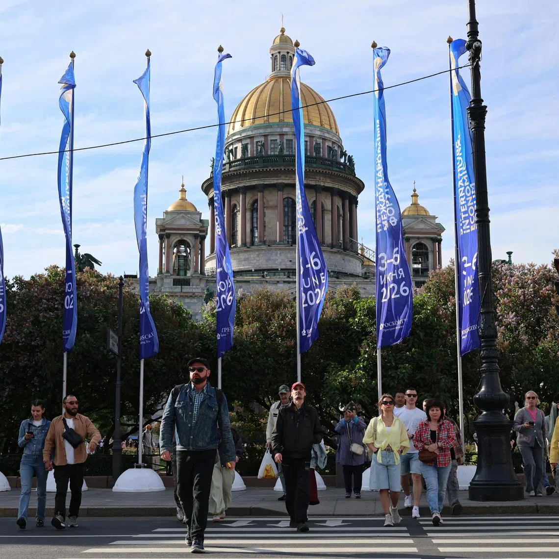 People cross the street near flags with the logo of the St. Petersburg International Economic Forum (SPIEF) flying in front of the St. Isaac's Cathedral on the eve of the forum's opening in Saint Petersburg, Russia June 2, 2026. REUTERS/Anastasia Barashkova