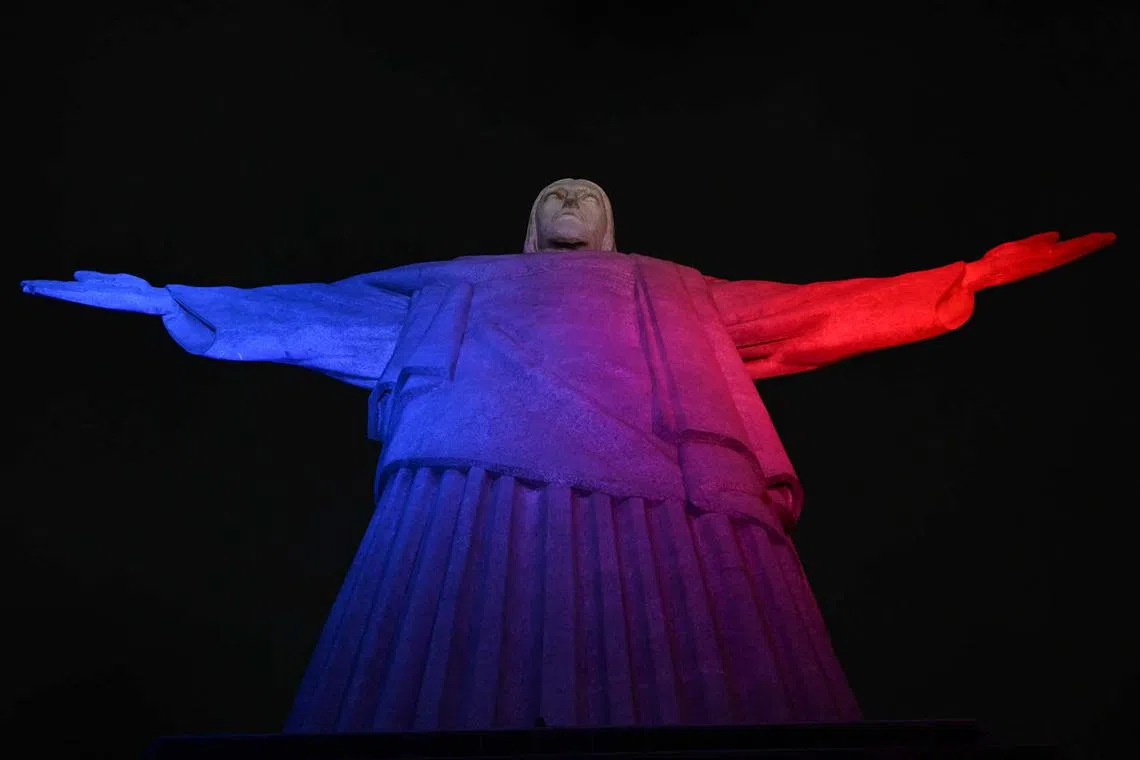 TOPSHOT - View of Christ the Redeemer lit up in red, white and Blue, representing the ties between France and Brazil, in Rio de Janeiro on November 12, 2024. (Photo by Pablo PORCIUNCULA / AFP)