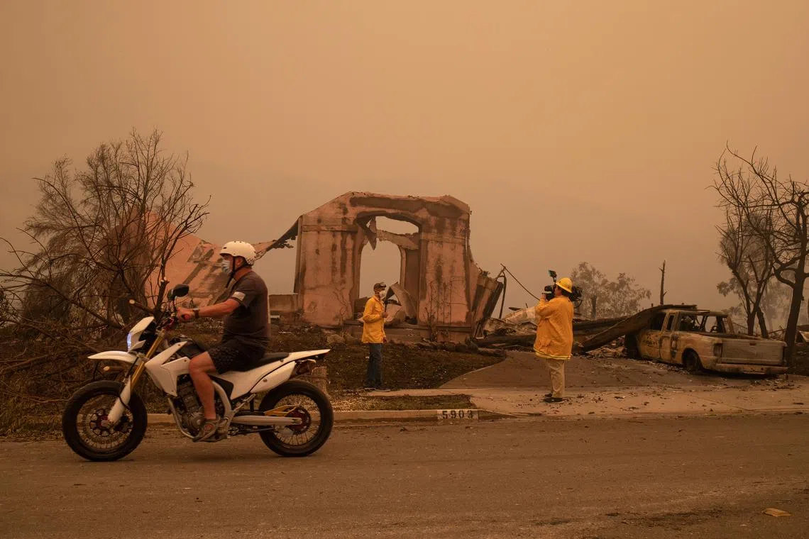 FILE PHOTO: A man rides past journalists reporting on the  aftermath of the Shady Fire after it advanced into the Skyhawk neighborhood of Santa Rosa, California, U.S. September 28, 2020. REUTERS/Adrees Latif/File Photo