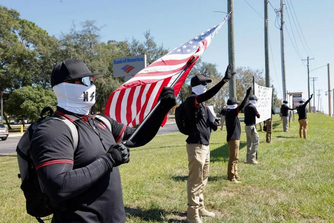 Members of the white nationalist group NatSoc Florida wave to motorists as they hold banners against U.S. support for Israel, during the Israeli-Hamas conflict, in Lady Lake, Florida, U.S., October 21, 2023. REUTERS/Joe Skipper/File Photo