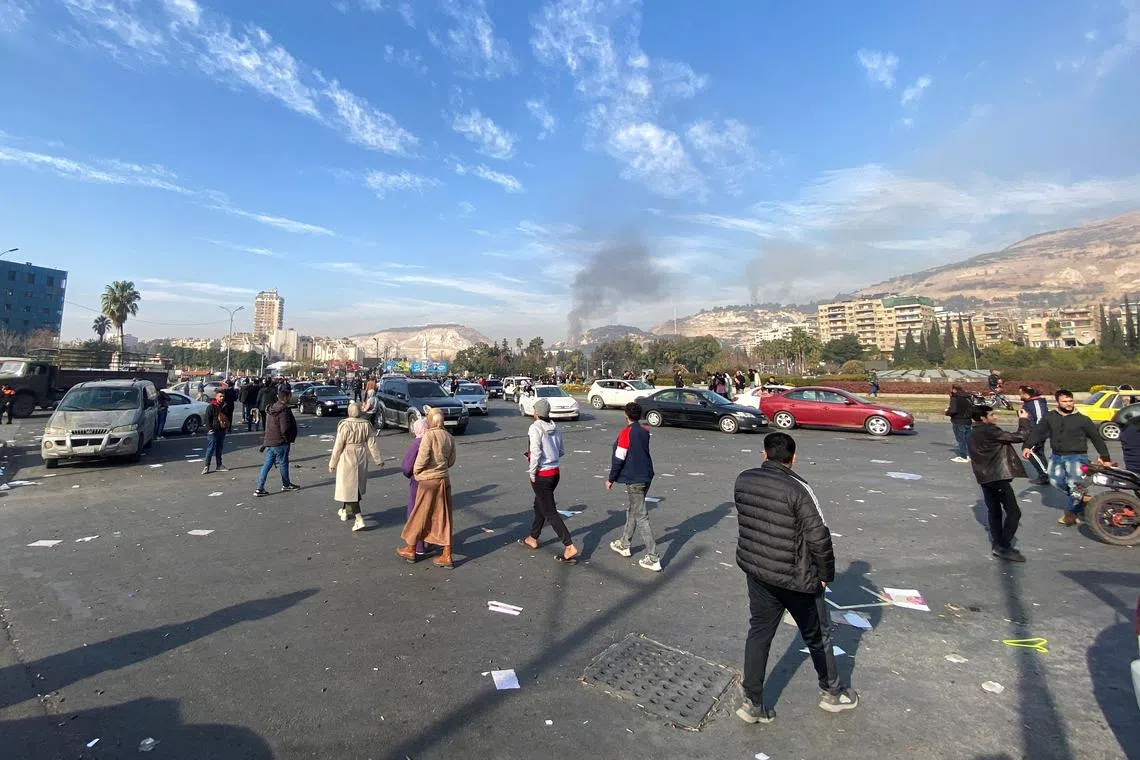 Smoke rises as people gather in Damascus, after Syrian rebels said on Sunday that they have ended Bashar al-Assad's 24-year authoritarian rule, in their first announcement on state television following a lightning offensive that took the world by surprise, Syria December 8, 2024. REUTERS/Firas Makdesi