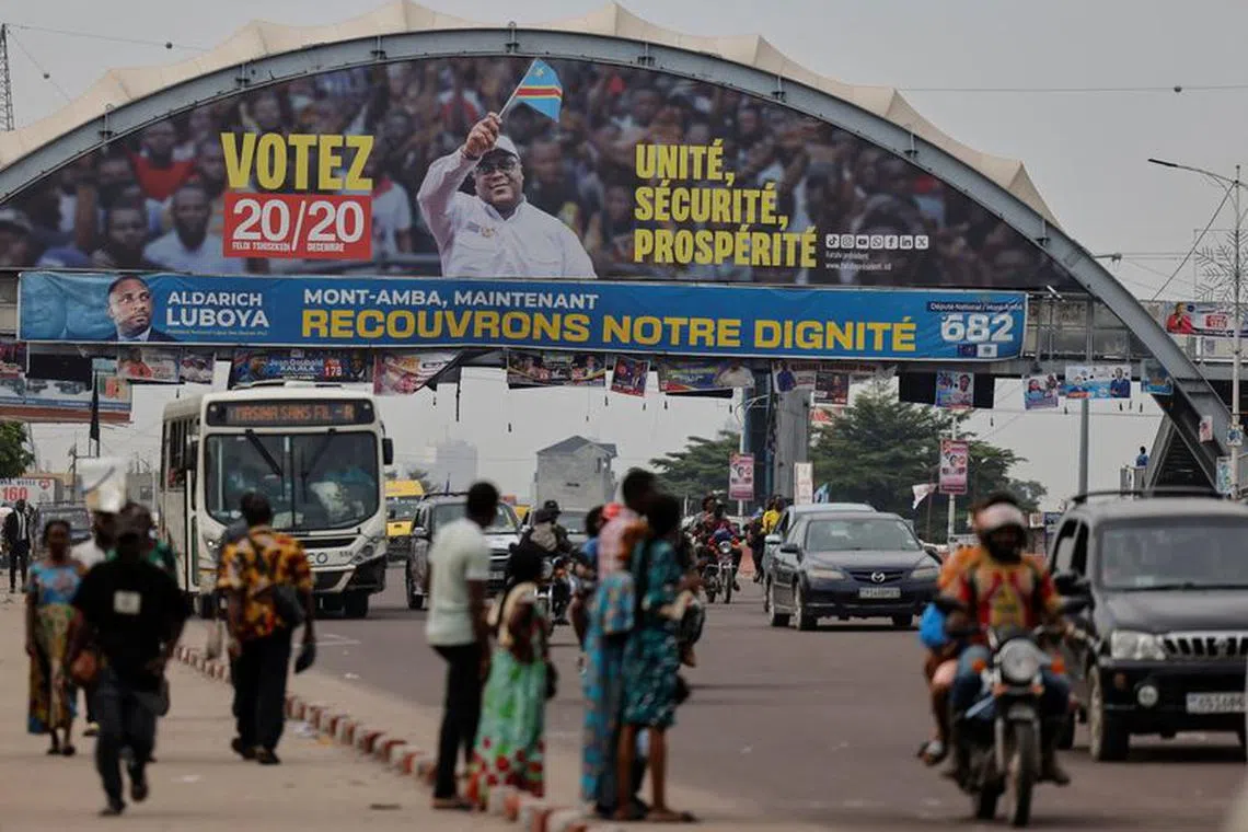 FILE PHOTO: People wait for transport in front of a campaign poster of the Democratic Republic of Congo's President Felix Tshisekedi for the upcoming presidential elections, in Kinshasa, the Democratic Republic of Congo December 16, 2023. REUTERS/Zohra Bensemra/FILE PHOTO
