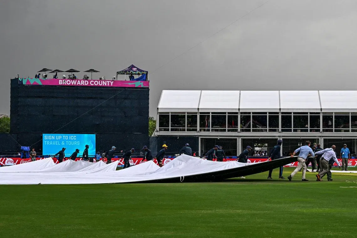 Ground staff pull a tarp over the cricket field as the US v Ireland T20 World Cup match was cancelled because of bad weather at Central Broward Park & Broward County Stadium in Lauderhill, Florida, on June 14, 2024. The US advanced to the Super Eight stage and former champions Pakistan were eliminated.