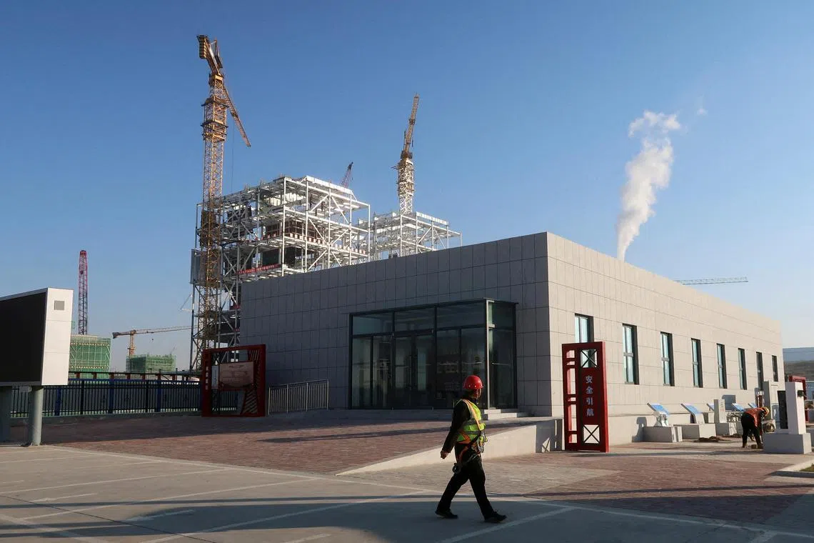 FILE PHOTO: A worker walks past cranes at Yushen Yuheng power plant, a coal-fired power plant under construction, in Yulin, Shaanxi province, China November 21, 2023. REUTERS/Ella Cao/File Photo