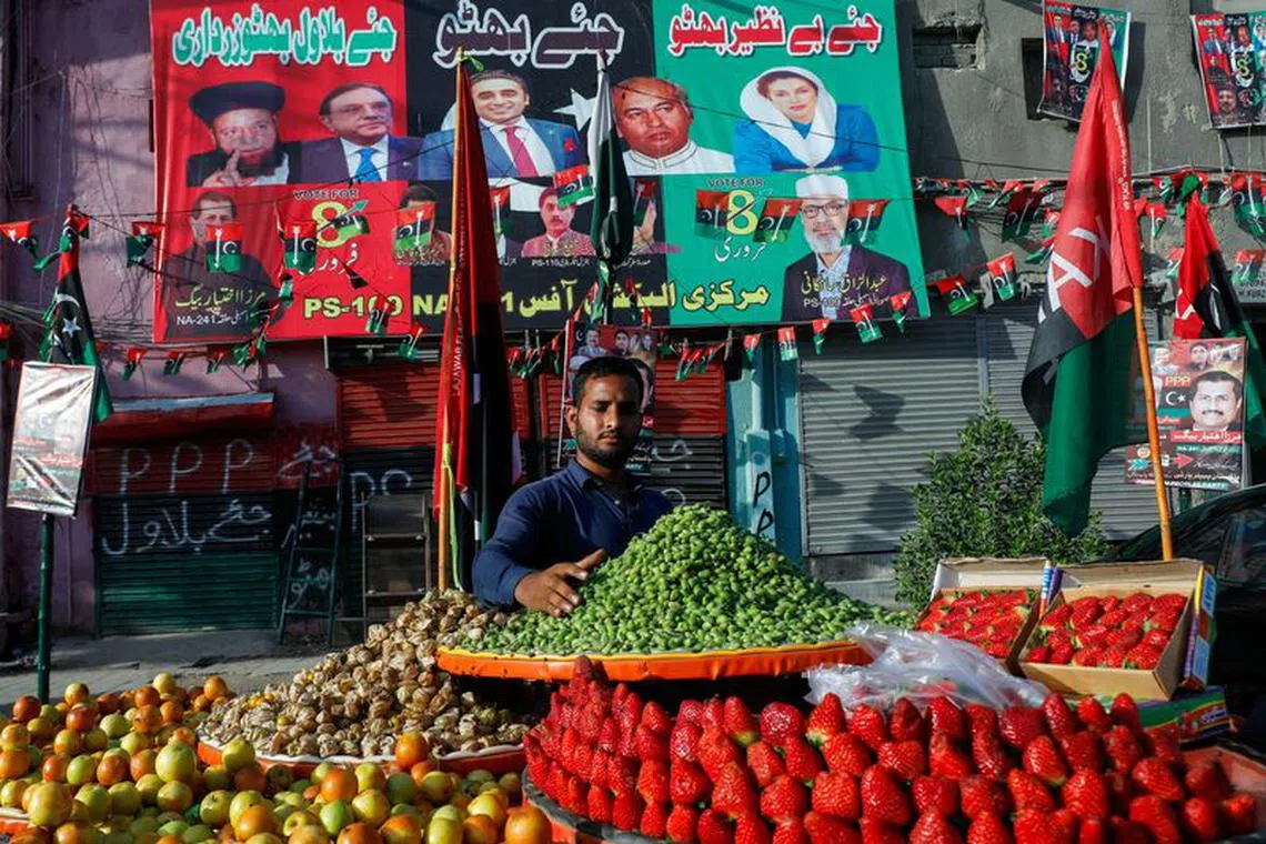 FILE PHOTO: A fruit vendor waits for customers in front of campaign posters of a political party, ahead of general elections, in Karachi, Pakistan February 1, 2024. REUTERS/Akhtar Soomro/File Photo