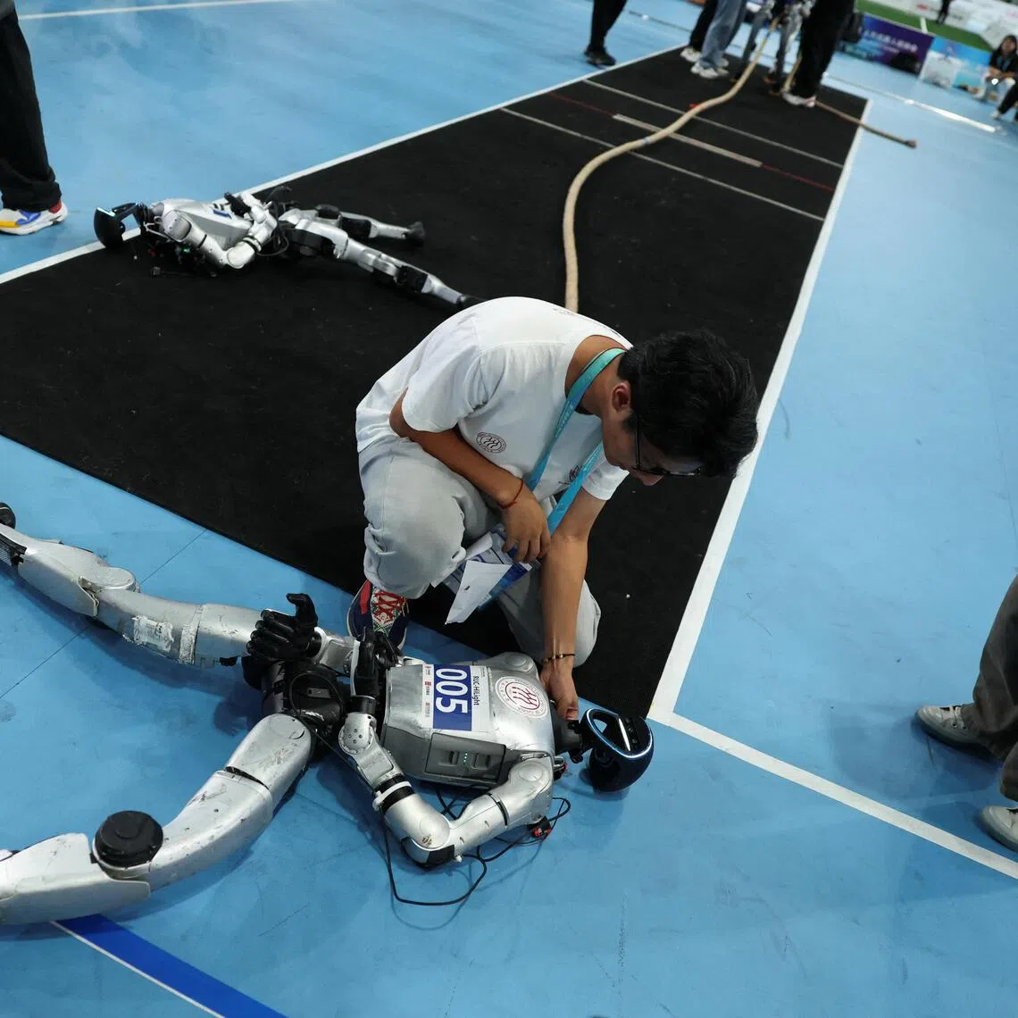 An engineer checks a fallen Unitree humanoid robot at the 2026 World Humanoid Robot Games in Beijing, China, on Aug 25.