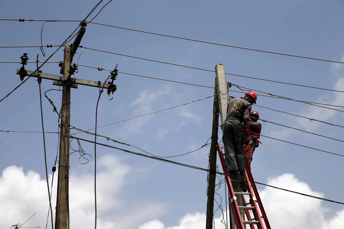 FILE PHOTO: Power officials stand on ladders to fix electric cables along a road in Egbeda dstrict in Nigeria's commercial capital Lagos, July 1, 2015. Picture taken July 1, 2015. REUTERS/Akintunde Akinleye/File Photo