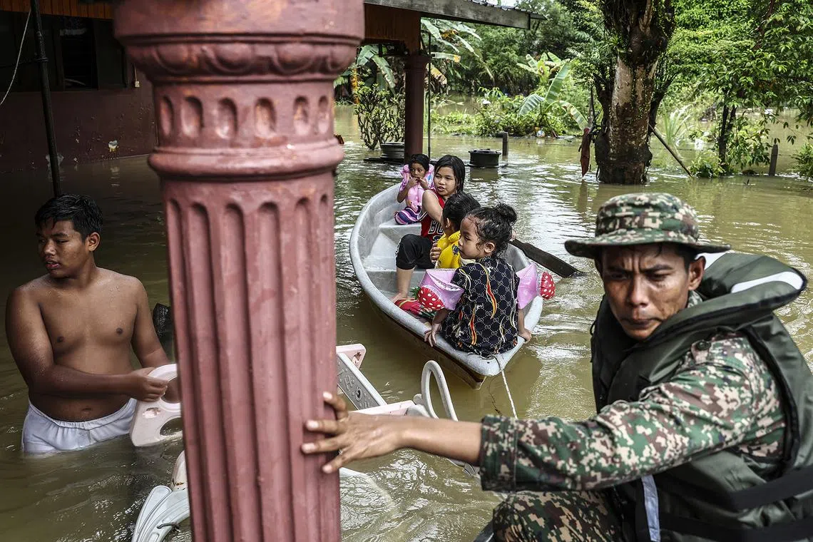 epa11045558 Malaysian Army personnel help victims who were affected by the flooding in Rantau Panjang, in the state of Kelantan, Malaysia, 27 December 2023. More than 28,000 people in four Malaysian states have been evacuated from their homes and are seeking shelter because of worsening flood conditions due to thunderstorms, heavy rains, and strong winds.  EPA-EFE/Stringer