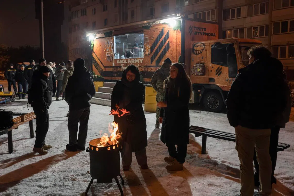 Residents gather around a fire for warmth at a mobile kitchen in Kyiv, Ukraine on Jan 28, 2026.