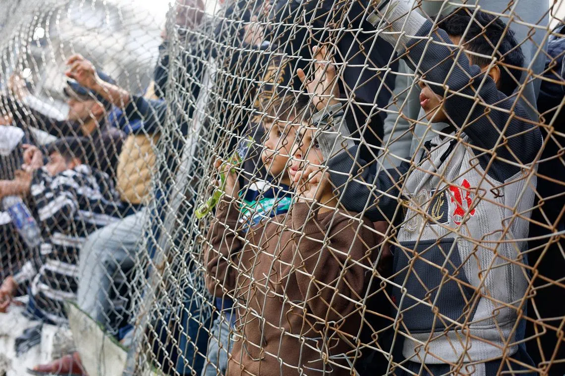 Palestinians watch, as people play football on a pitch in Gaza City.