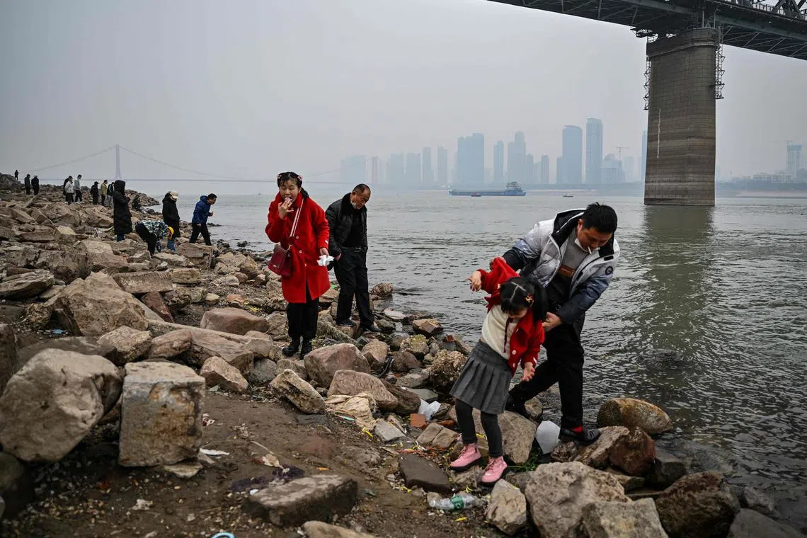 People stand on the riverbank of the Yangtze River in Wuhan, in China's central Hubei province, on Jan 22, 2023.