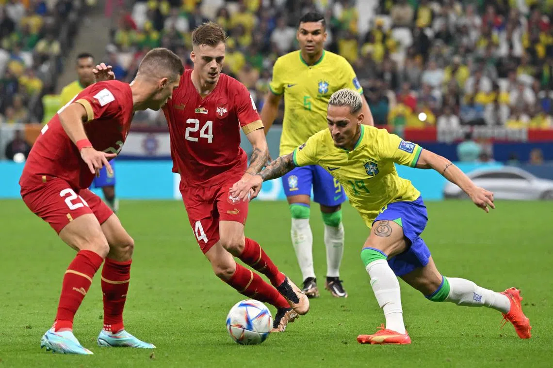 Brazil's forward #19 Antony (R)  fights for the ball with Serbia's midfielder #24 Ivan Ilic (C)  during the Qatar 2022 World Cup Group G football match between Brazil and Serbia at the Lusail Stadium in Lusail, north of Doha on November 24, 2022. (Photo by NELSON ALMEIDA / AFP)