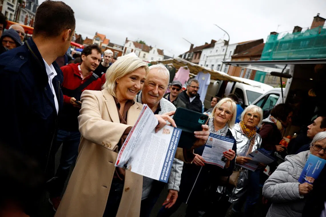FILE PHOTO: Marine Le Pen, French far-right leader and French far-right National Rally (Rassemblement National - RN) party candidate in the upcoming parliamentary elections, makes a selfie with supporters as she campaigns at a market in Henin-Beaumont, northern France, June 14, 2024. REUTERS/Sarah Meyssonnier/File Photo