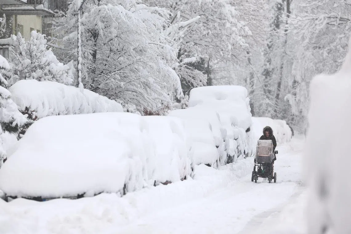 A woman pushes a trolley along a snow-covered street in Munich, Germany, on Dec 2, 2023.