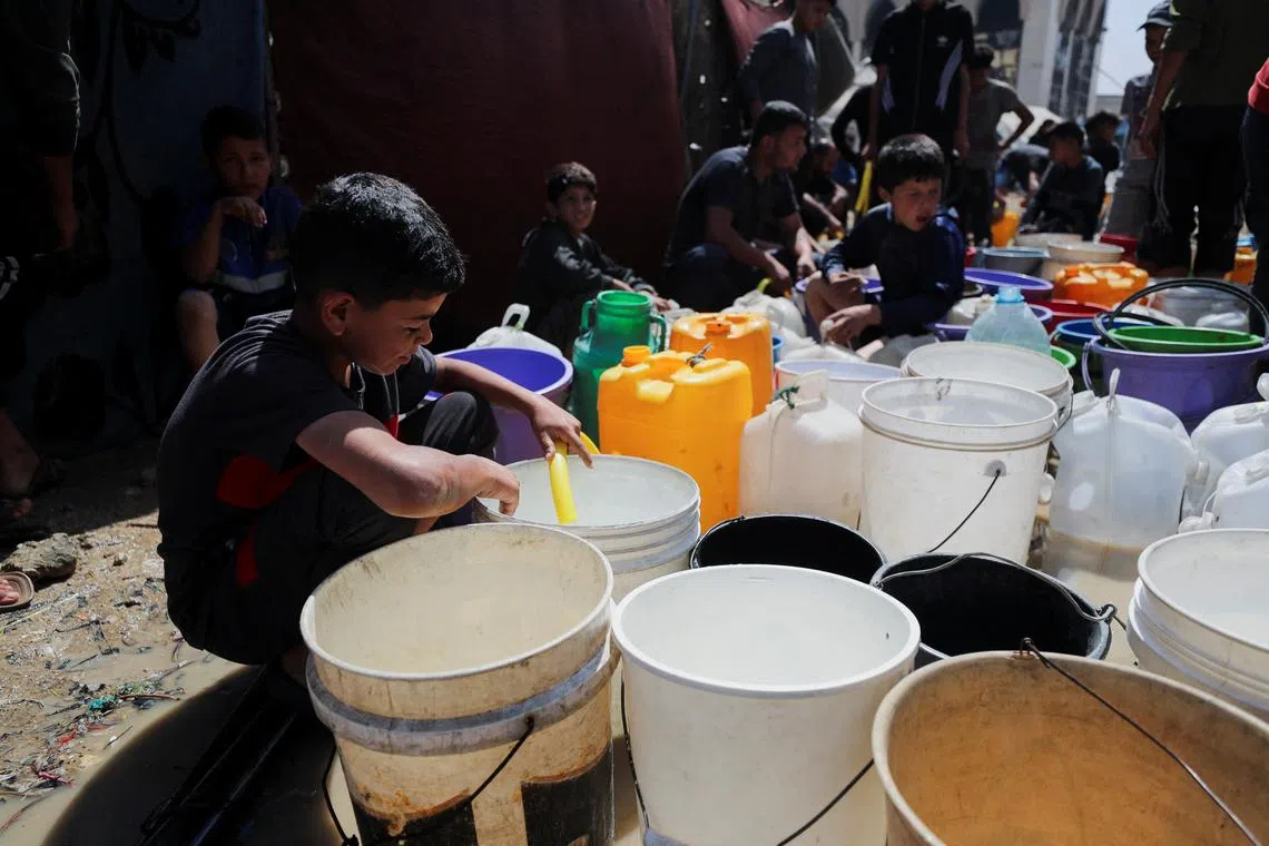 FILE PHOTO: Palestinian children fill water containers at a tent camp, in Gaza City, May 20, 2025. REUTERS/Mahmoud Issa/File Photo
