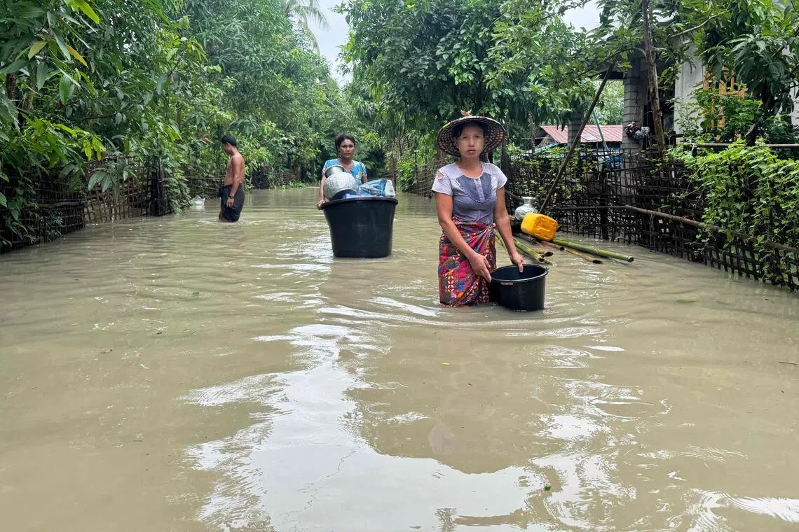 Residents wade through floodwaters in Kyauktaw, Myanmar’s western Rakhine state on July 10.