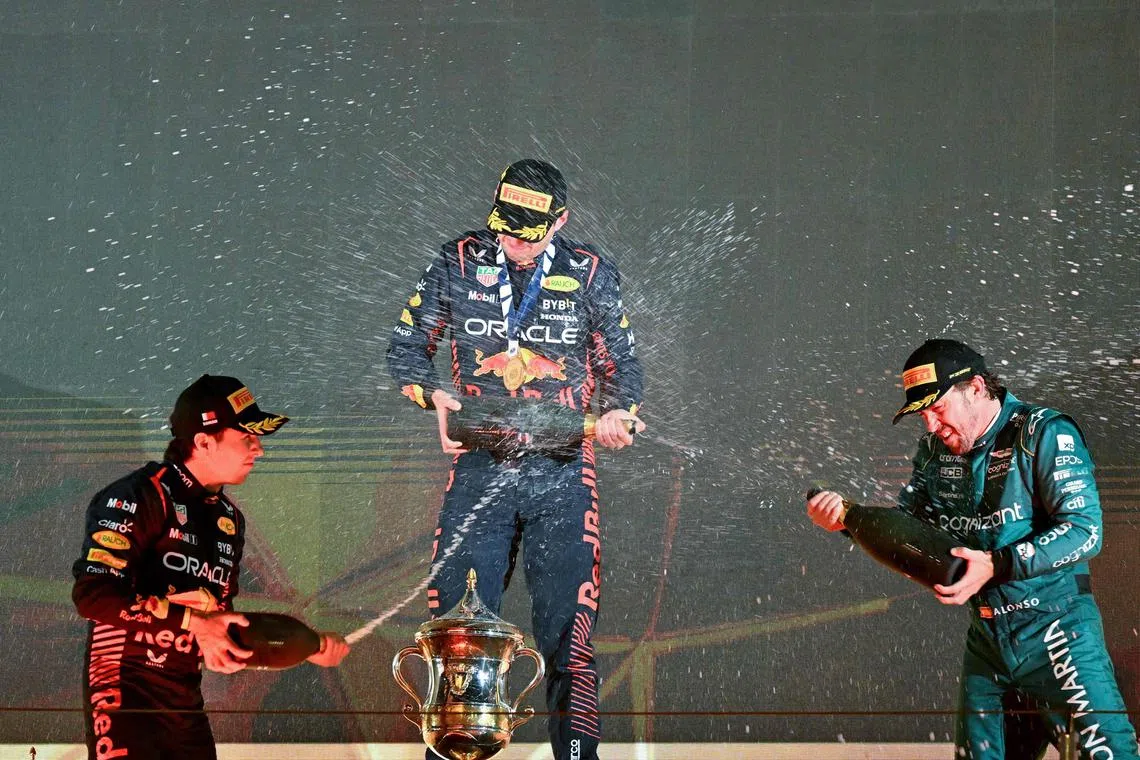 Bahrain Grand Prix runner-up Sergio Perez of Red Bull (left) and third-placed Aston Martin driver Fernando Alonso (right) spraying non-alcoholic champagne on winner Max Verstappen of Red Bull on the podium after the Bahrain Grand Prix in Sakhir. 