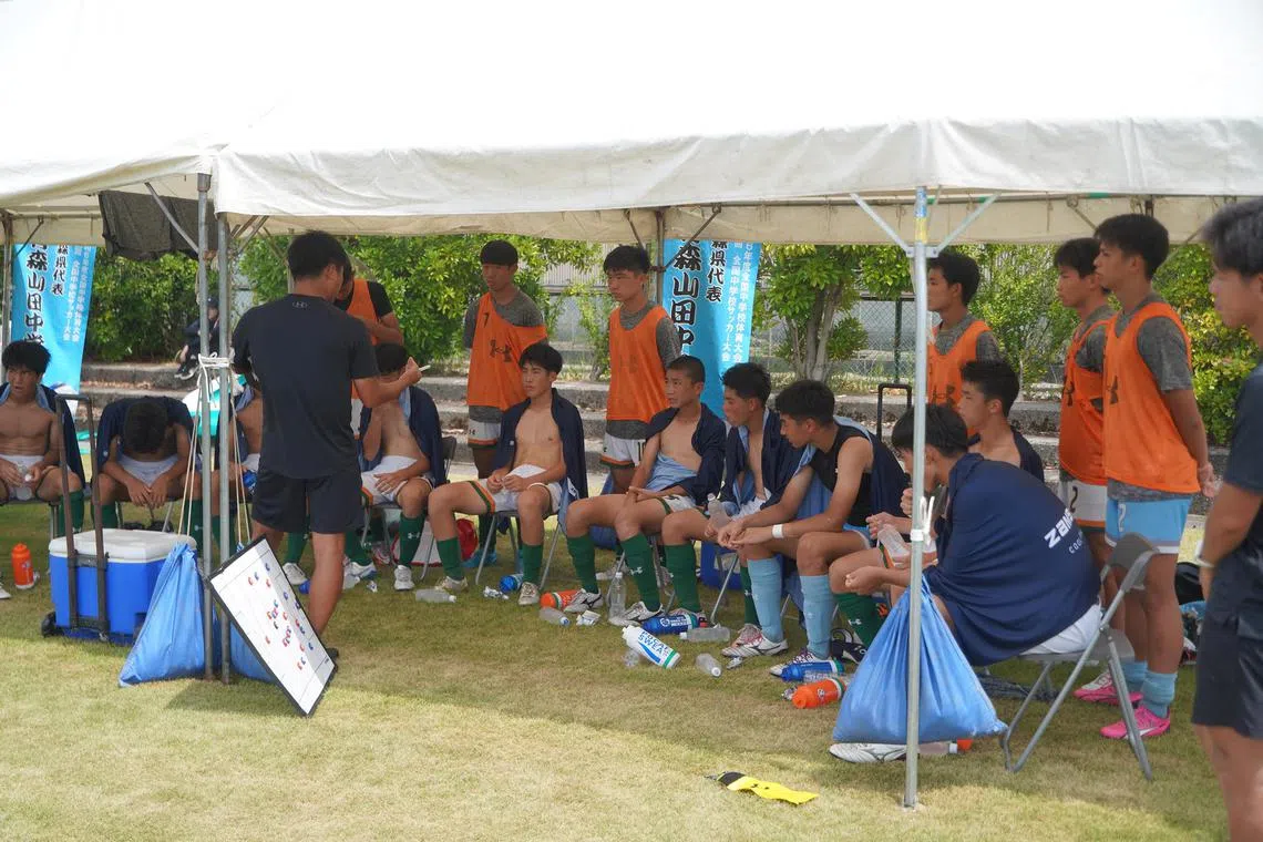 wsheat - Players from Aomori Yamada Junior High School in Aomori Prefecture listen to their coach as they cool off during half-time by removing their jerseys, draping themselves in cooling towels and hydrating with isotonic drinks, in their match against Niigata's Kobari Junior High School  at the 55th National Junior High Football Tournament in Komatsu, Ishikawa Prefecture, on Monday, August 19, 2024. ST PHOTO: WALTER SIM