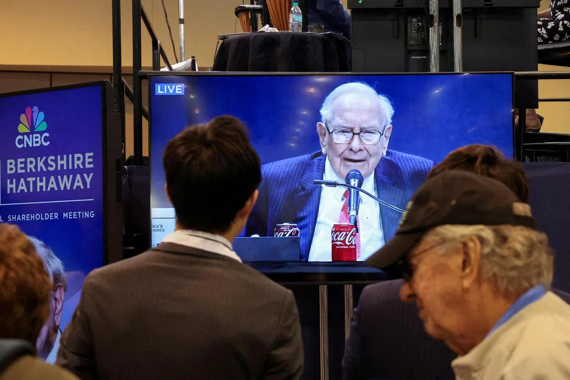 FILE PHOTO: People watch as Berkshire Hathaway chairman Warren Buffett is seen on a screen speaking at the Berkshire Hathaway Inc annual shareholders' meeting, in Omaha, Nebraska, U.S., May 3, 2025.  REUTERS/Brendan McDermid/File Photo
