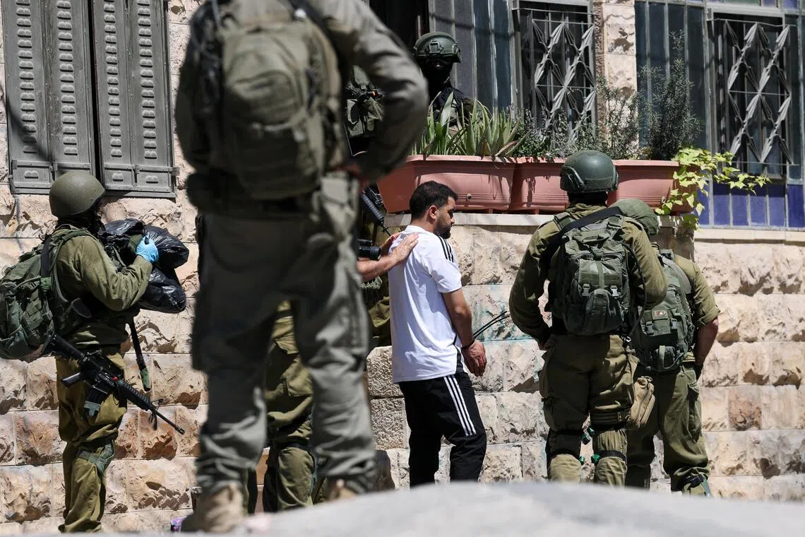 Israeli soldiers talking to a Palestinian man, as they conduct a raid in Anata, in the Israeli-occupied West Bank, on Sept 8.