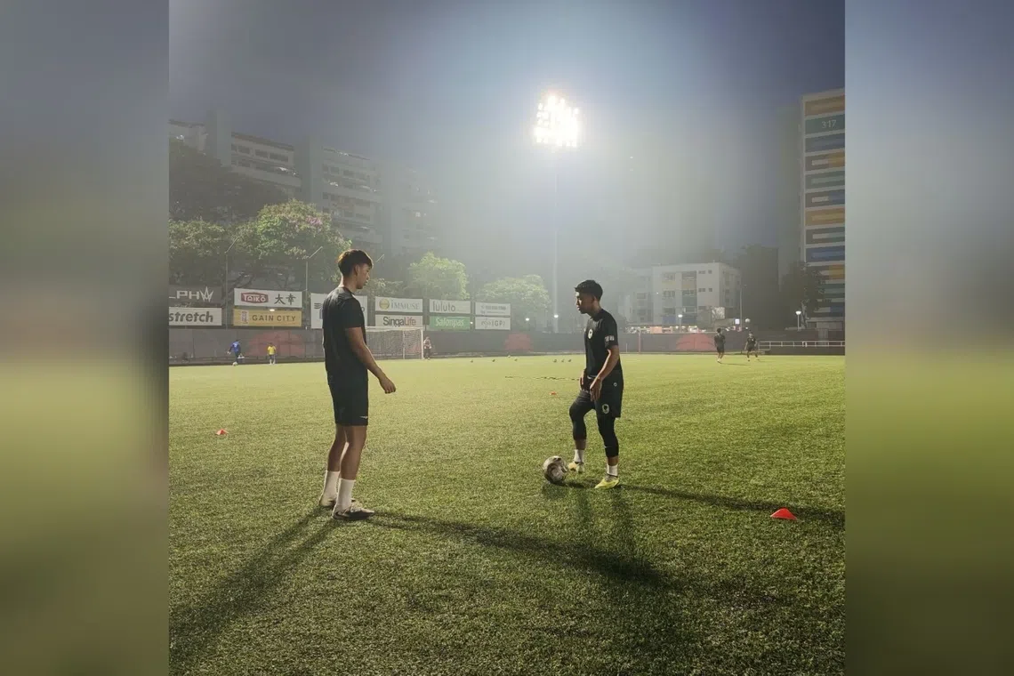Tanjong Pagar United players Kieran Teo (left) and Syahrul Sazali passing the ball during a training session amid hazy conditions at Jurong East Stadium.