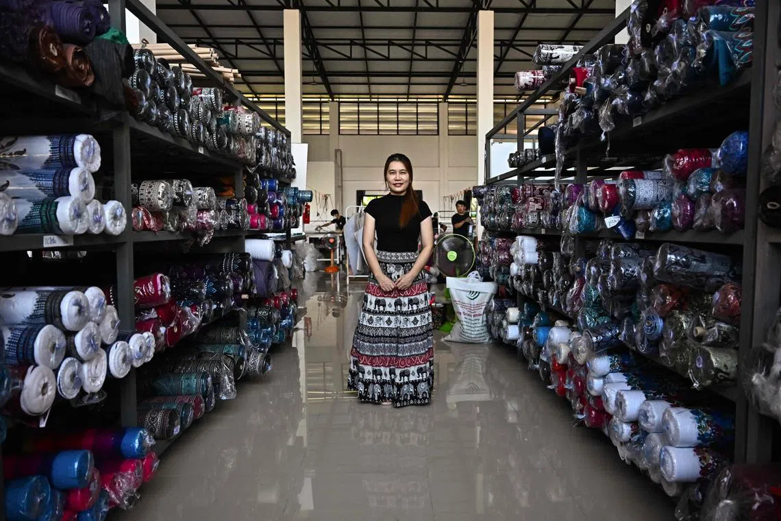 This photo taken on October 18, 2023 shows factory owner and director Kingkarn Samon standing in between shelves holding bolts of elephant print fabric at Chinrada Garment co. in the northern Thai province of Chiang Mai. An elegant Thai socialite poses in sunglasses, a designer handbag discreetly visible in the Instagram photo, her stylish outfit completed by a pair of... elephant print pants? (Photo by Lillian SUWANRUMPHA / AFP) / TO GO WITH "THAILAND-ECONOMY-FASHION-TOURISM" by Chayanit ITTHIPONGMAETEE and Rose TROUP BUCHANAN)