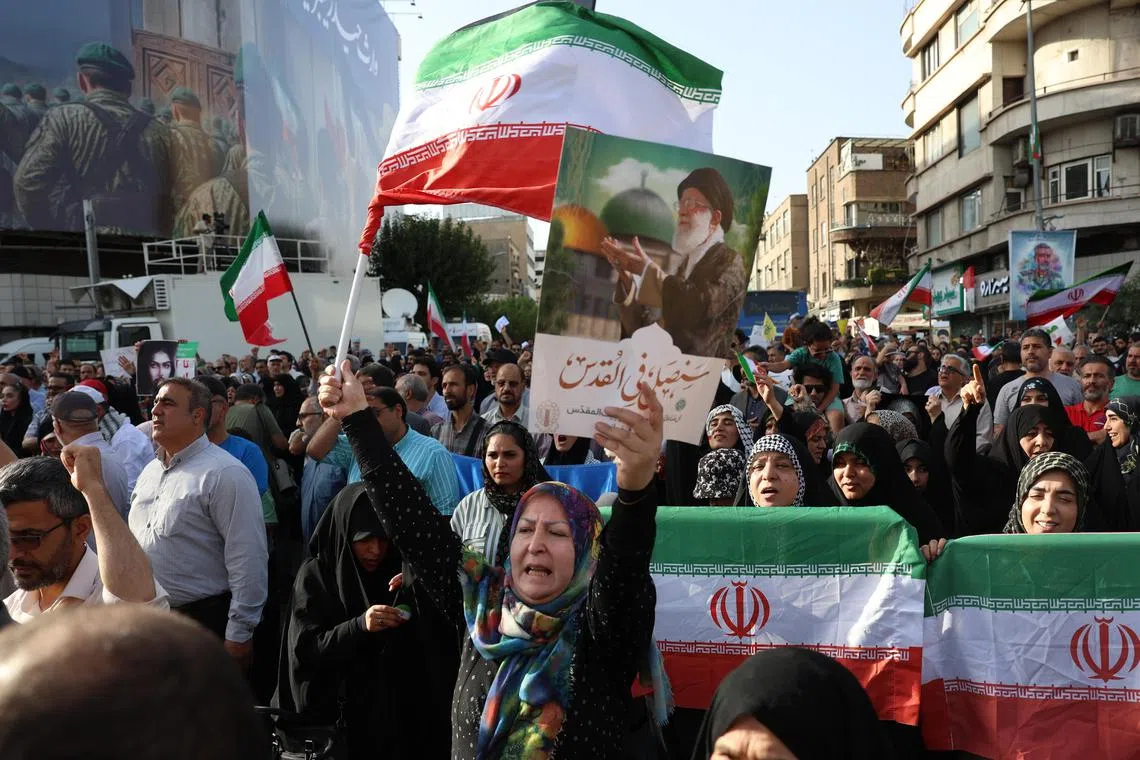 An Iranian woman waving a national flag and holding up a placard depicting Iran's Supreme Leader Ayatollah Ali Khamenei during an anti-US and anti-Israel demonstration in Tehran on June 22.  