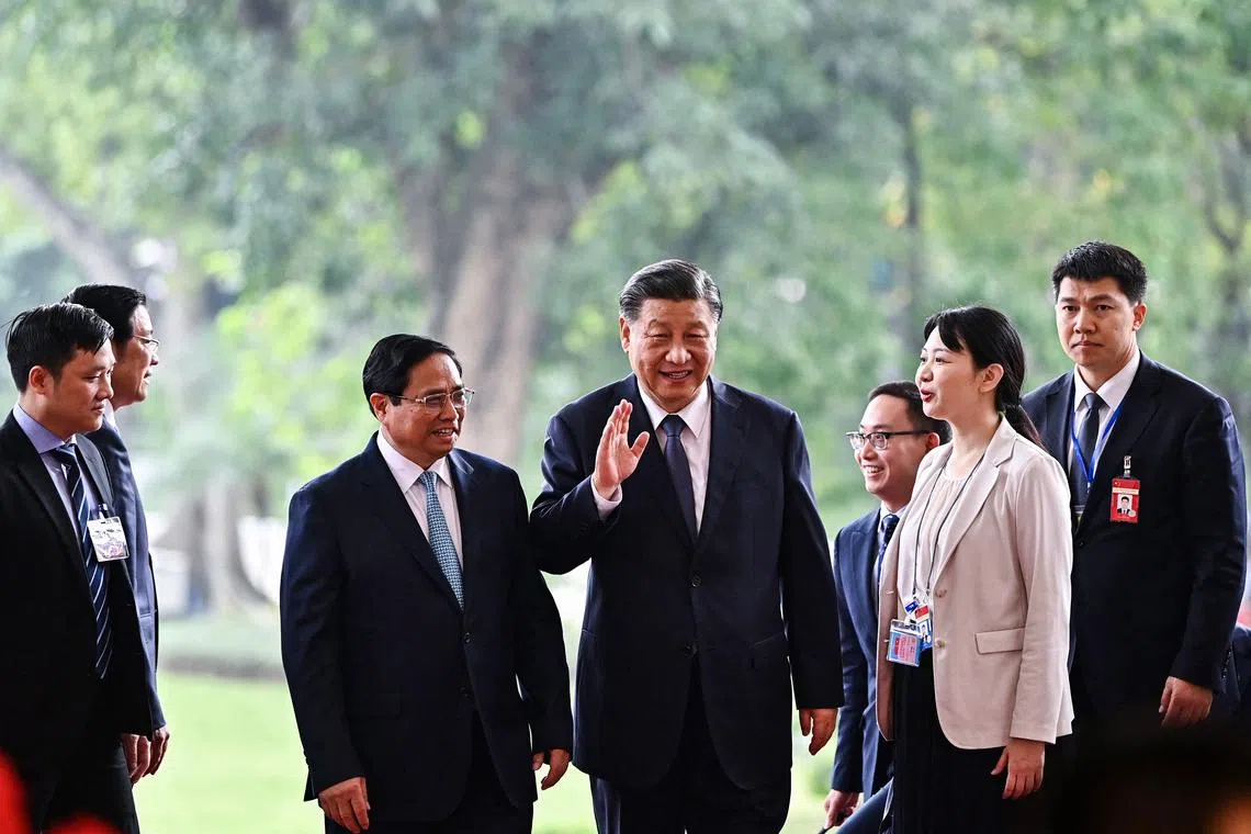 Vietnam's Prime Minister Pham Minh Chinh (centre, left) welcomes Chinese President Xi Jinping (centre, right), in Hanoi on Dec 13.