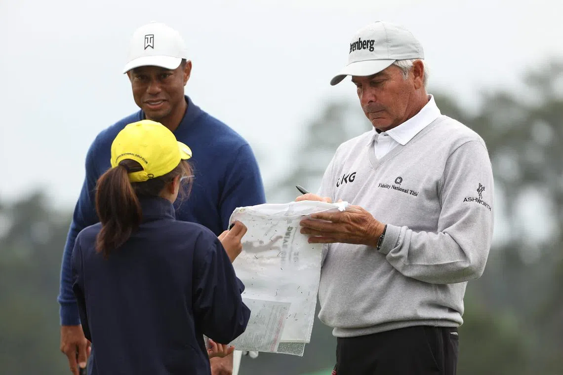 Fred Couples signing a pin flag for Ashley Kim, winner of the 7-9 Drive, Chip and Putt Championship group, during a practice round at the Masters at Augusta National.