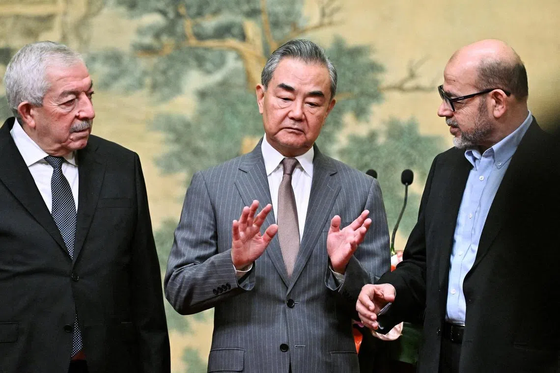 Mahmoud al-Aloul, Vice Chairman of the Central Committee of Palestinian organisation and political party Fatah, China's Foreign Minister Wang Yi, and Mussa Abu Marzuk, senior member of the Palestinian Islamist movement Hamas, attend an event at the Diaoyutai State Guesthouse in Beijing on July 23, 2024. PEDRO PARDO/Pool via REUTERS     TPX IMAGES OF THE DAY     