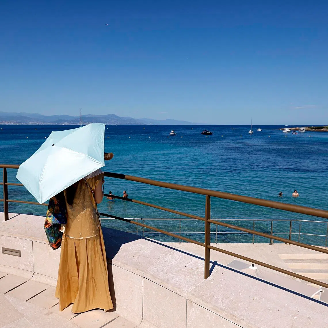 A woman shelters from the sun under an umbrella at Cap d’Antibes, southern France, on Jul 2.
