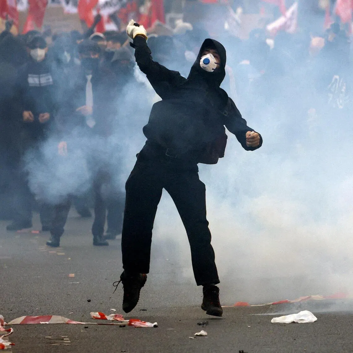 A masked protester throwing an object, amid clashes with French police in Paris on Oct 6.
