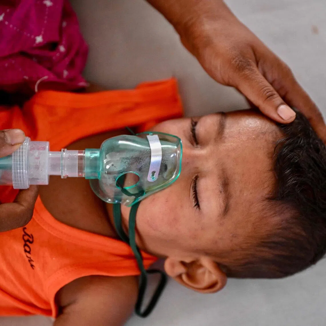 A mother holds a nebulizer on the face of her child receiving treatment for measles in a paediatric ward at a hospital in Dhaka on April 9.