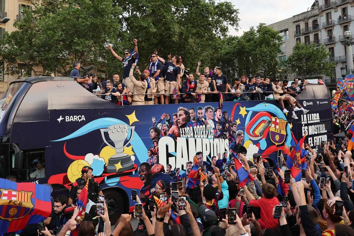 Barcelona's men team aboard a open-top bus followed by the women's team (out of frame), to celebrate their La Liga titles in Barcelona on May 15, 2023.
