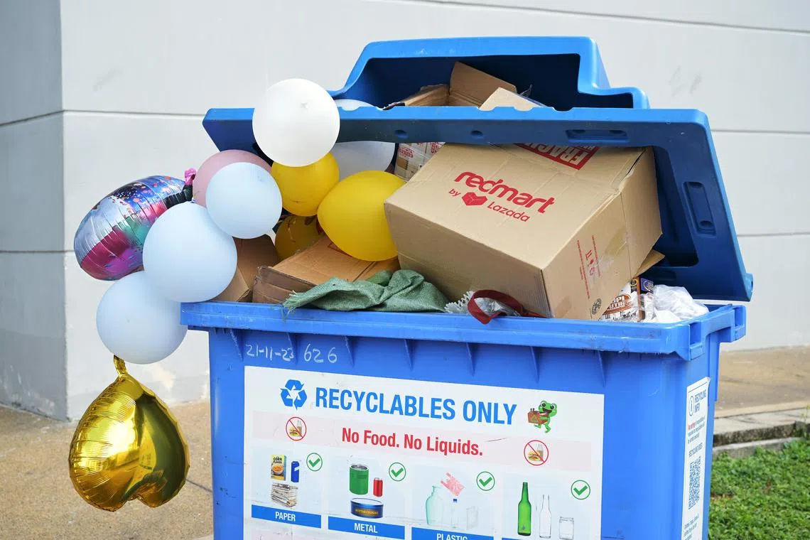 An overflowing recycling bin that's filled with items not meant for recycling.