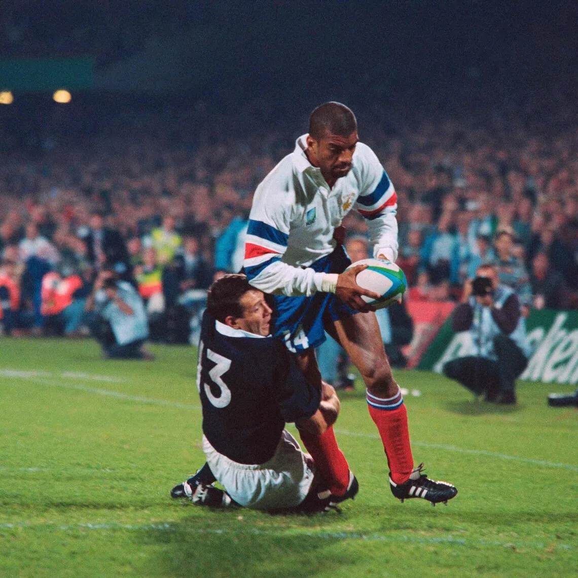 French right wing Emile N'Tamack is tackled by Scotland's centre Scott Hastings as he scores a try in the last minute of the decisive pool D Rugby World Cup at Loftus in Pretoria on June 3, 1995.