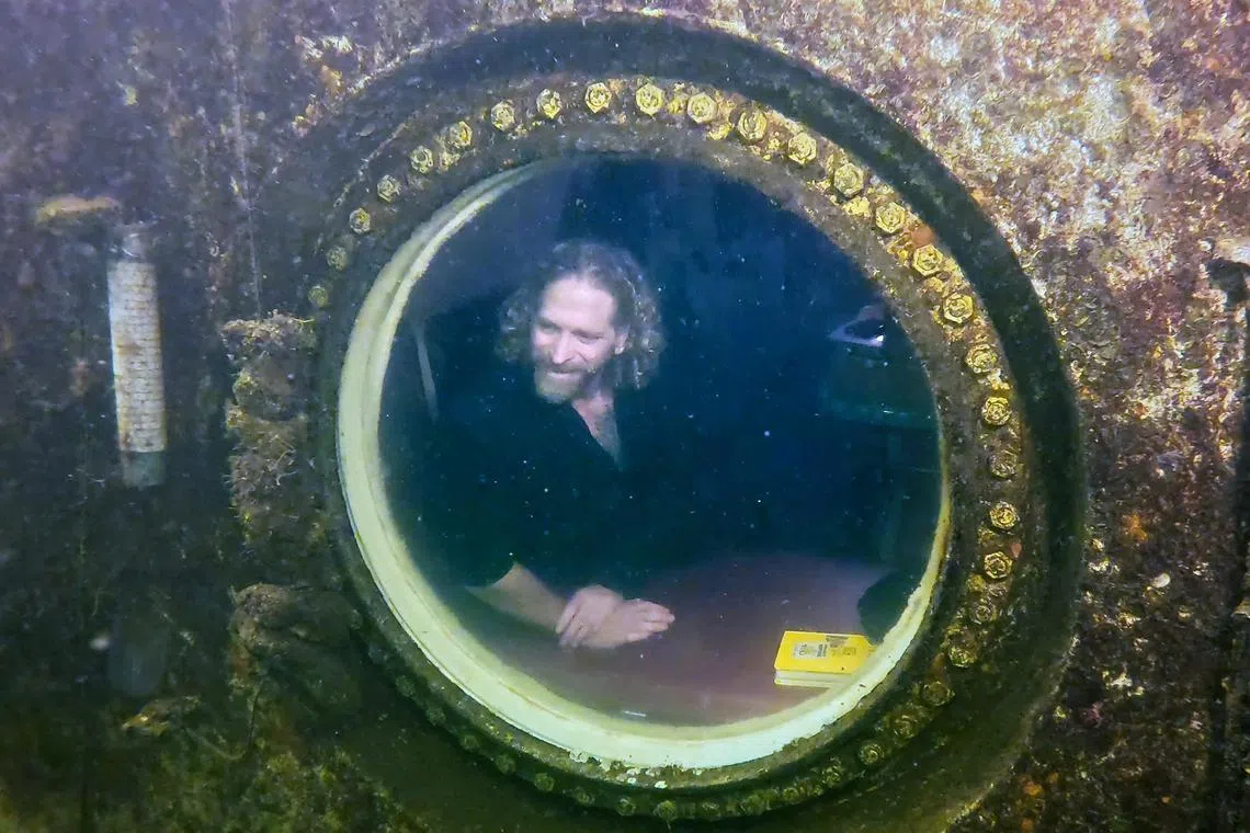 Dr Joseph Dituri peers out of a large porthole inside the Jules' Undersea Lodge, in a Key Largo lagoon, Florida Keys, Florida.