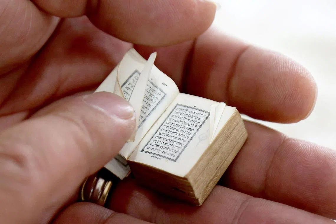 Mario Prushi holding one of the smallest Koran (Islam's holy book), the size postage-stamp size with a cover crafted from gold embroidered velvet, in Tirana, Albania on April 17, 2023. The ritual is always the same. Mario Prushi carefully washes his hands and face before kissing and pressing one of the world’s smallest Korans to his forehead. For generations, the postage-stamp sized book has been passed down in his family surviving authoritarian governments, war, and the perils of time. 