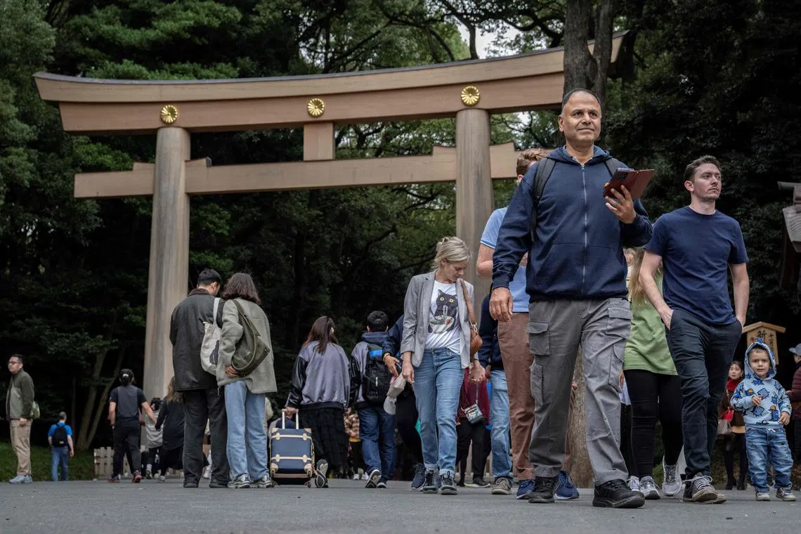 People walk past a Torii gate at Meiji shrine in Tokyo on Nov 14, 2024. 