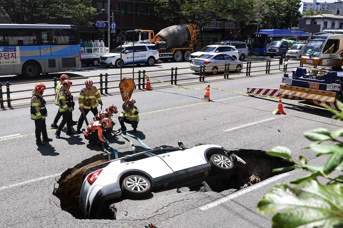 epa11570501 Firefighters prepare to remove a car from a sinkhole that emerged in the middle of a road in Seoul, South Korea, 29 August 2024. According to fire authorities, two people were injured after a car plunged into the sinkhole. EPA-EFE/YONHAP SOUTH KOREA OUT