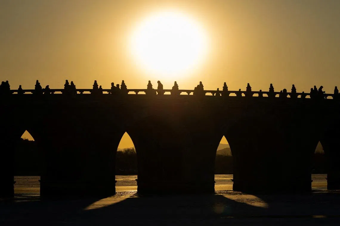 People walk on Seventeen-Arch Bridge, also known as Shiqikong Qiao, as the sun sets at Summer Palace in Beijing, China, on Jan 20.
