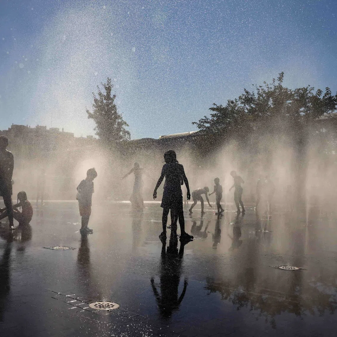 People cooling off at a fountain at Madrid Rio Park amid heatwave conditions in Madrid, Spain, in 2024.